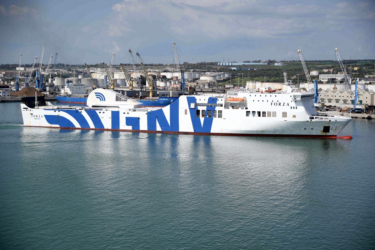 Die GNV-Fähre Forza liegt im Hafen von Civitavecchia, dahinter Hafenkräne und Tanklager